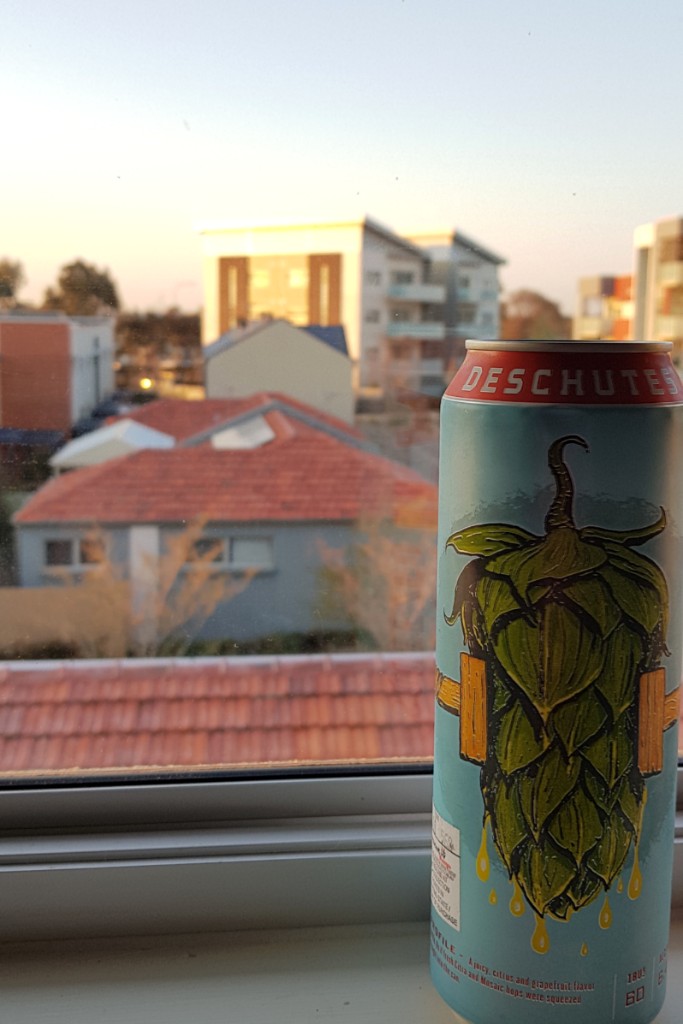 A big can of PNW on a windowsill overlooking buildings.
